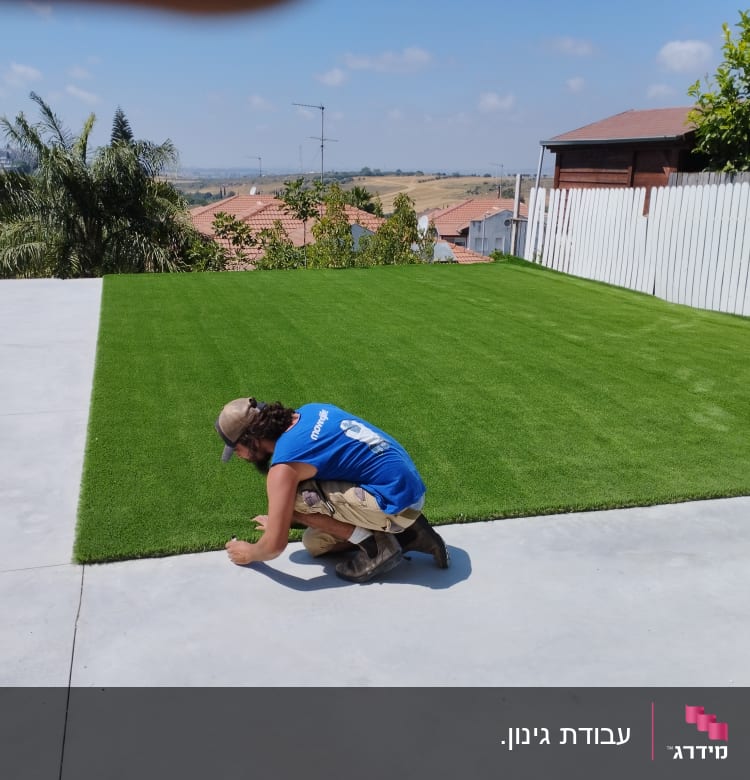 אדם מתקין דשא סינתטי על משטח בטון